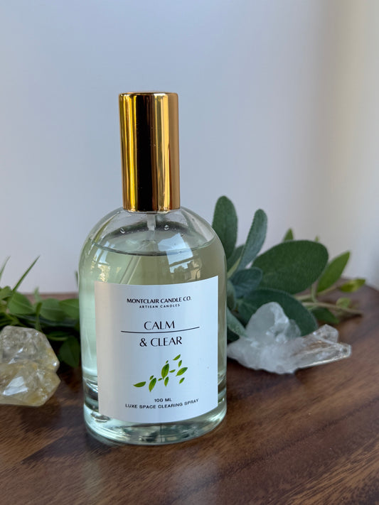 Clear bottle with gold cap on a wooden surface with greenery