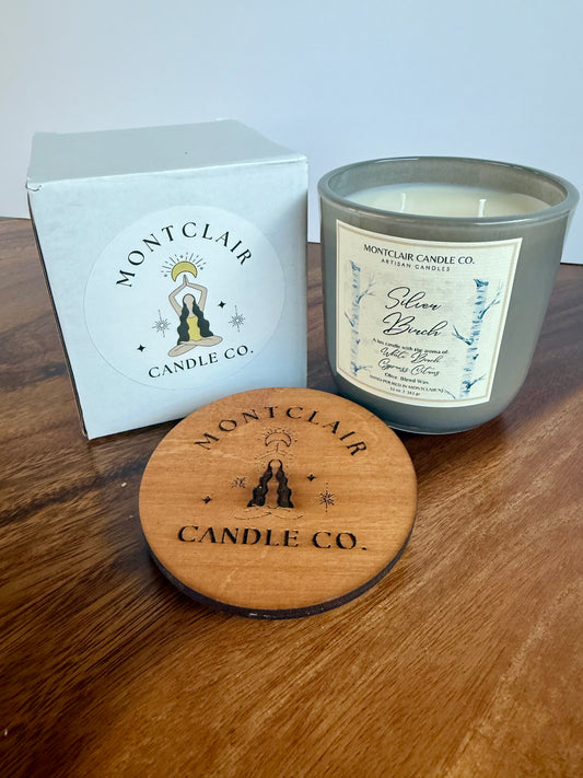 Montclair Candle Co. candle with wooden coaster and packaging on a wooden surface