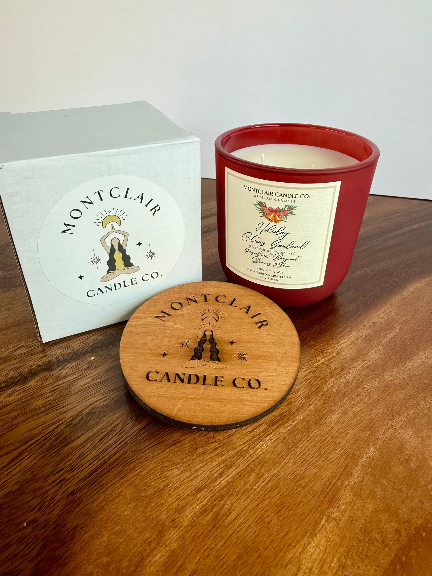 Montclair Candle Co. candle with lid and packaging on a wooden surface