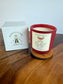 Red candle with a label and Montclair Candle Co. box on a wooden surface