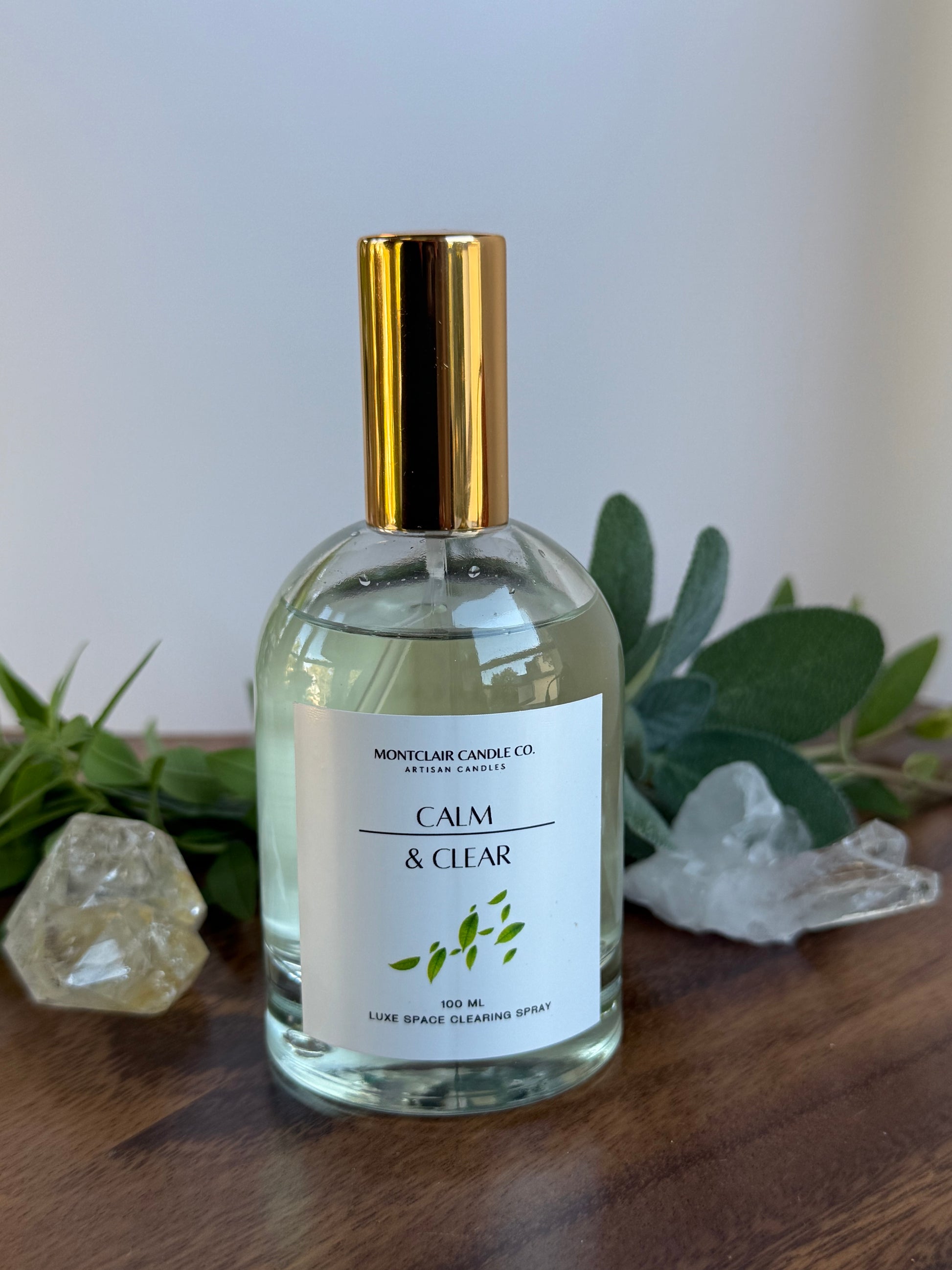 Bottle of 'Clear & Calm' product on a wooden surface with plants in the background