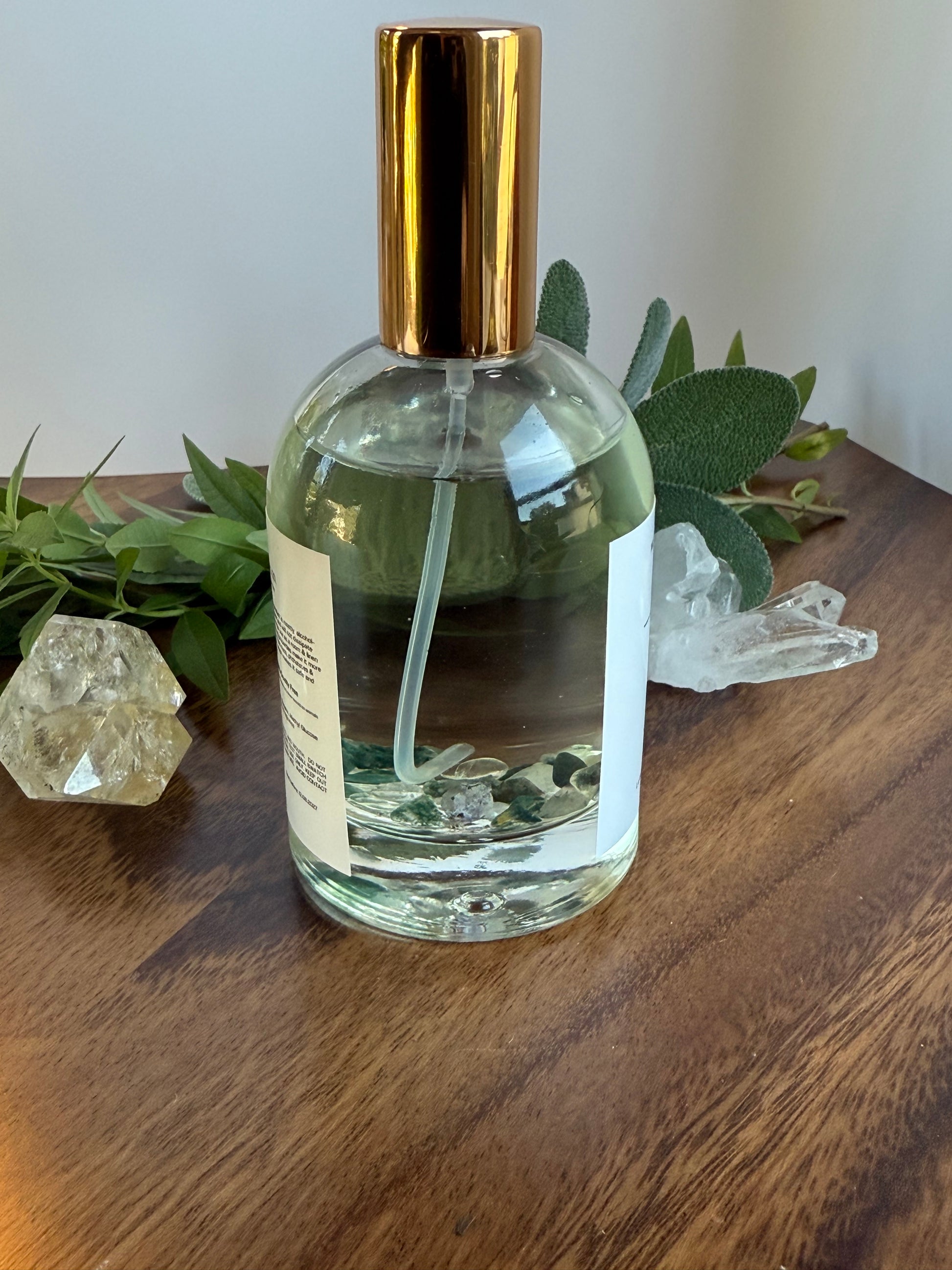 Clear glass bottle with gold cap on a wooden surface with greenery