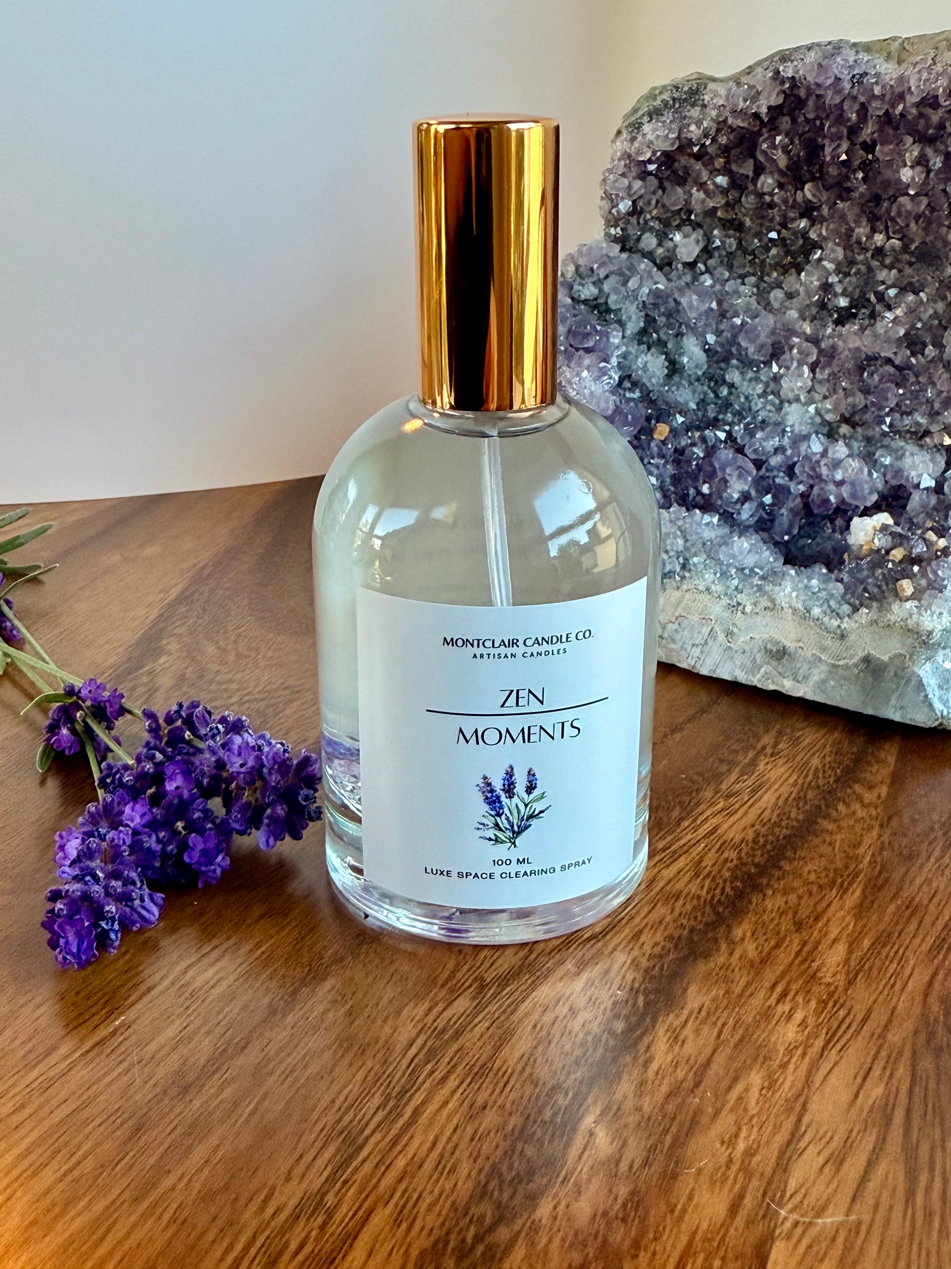 Bottle of 'Zen Moments' diffuser with lavender flowers and a crystal on a wooden surface