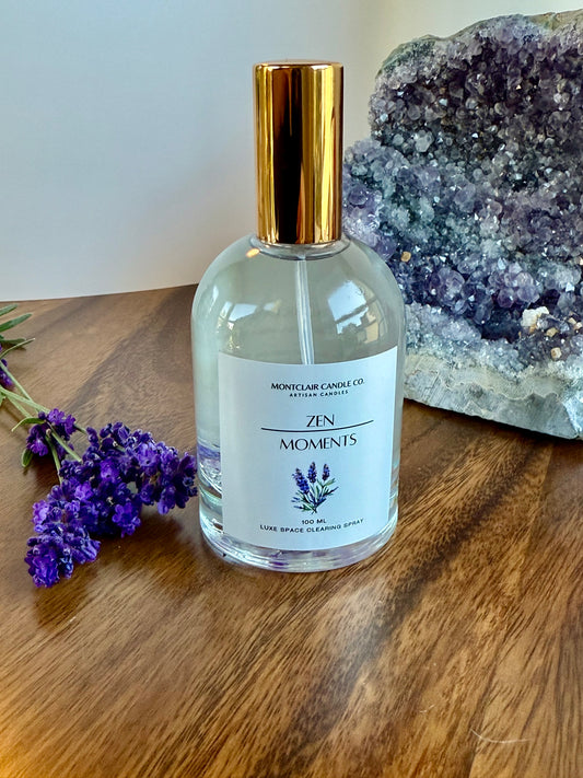 Perfume bottle labeled 'Zen Moments' on a wooden surface with lavender and crystals in the background