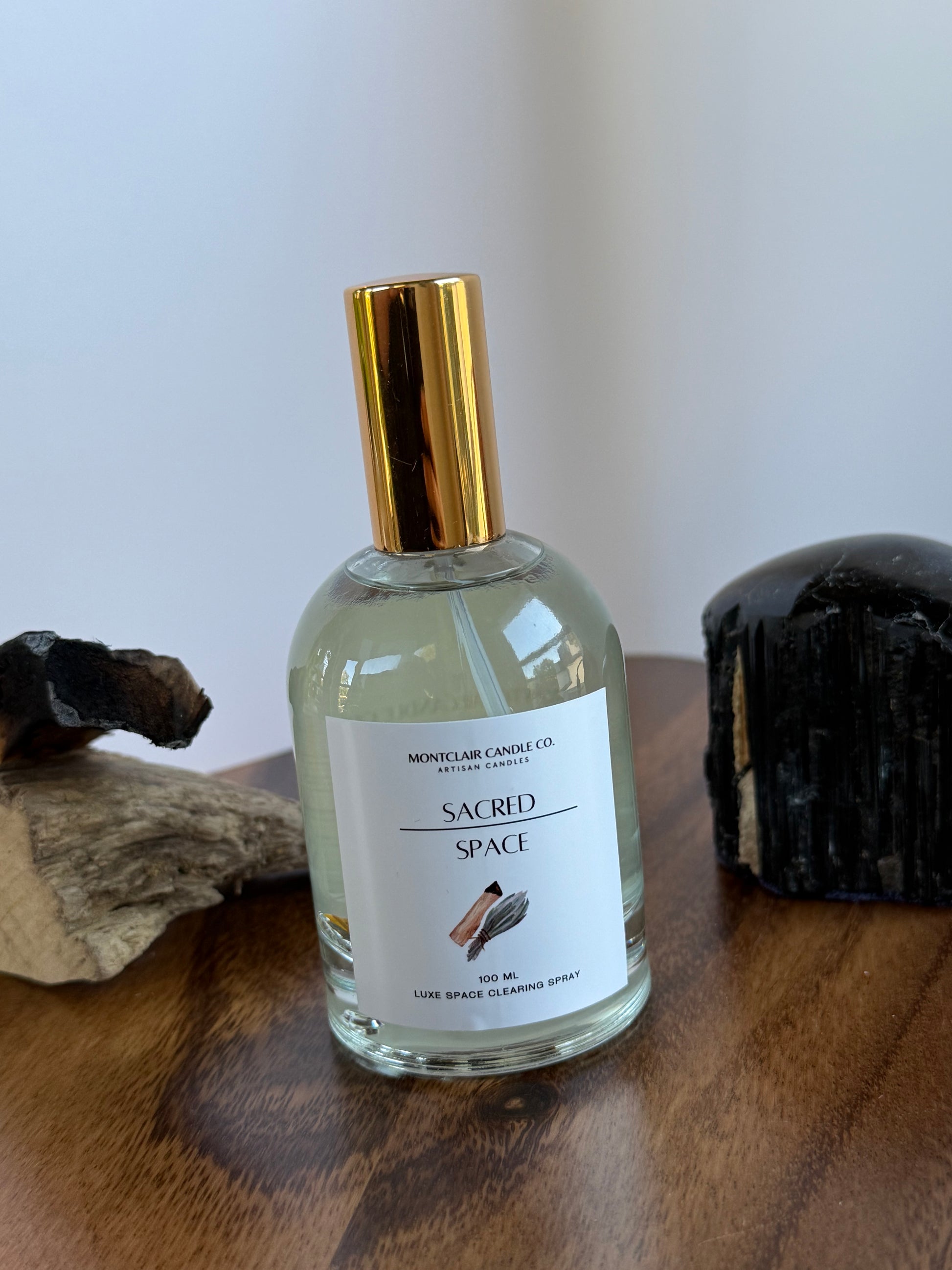 Bottle of 'Sacred Space' perfume on a wooden surface with a white background