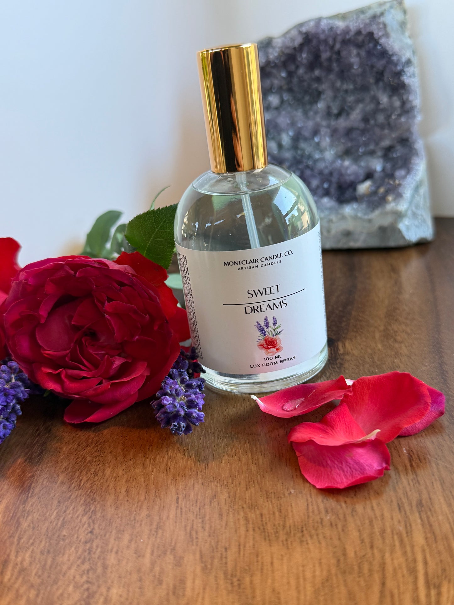 Bottle of perfume with gold cap on a wooden surface with flowers and crystals