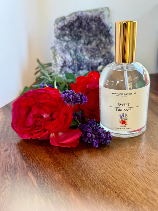 Bottle of 'Sweet Dreams' perfume with red roses and lavender on a wooden surface