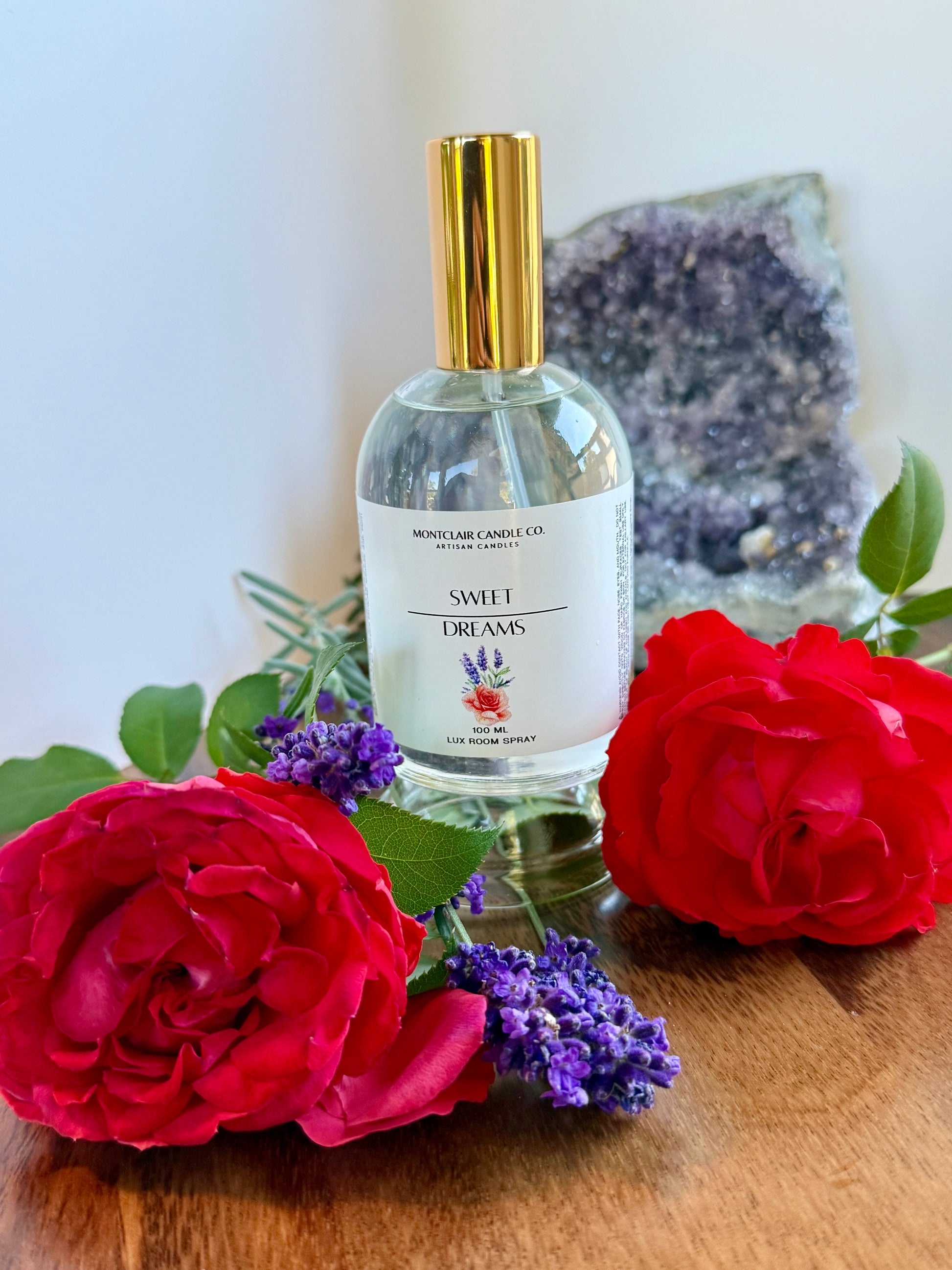 Perfume bottle labeled 'Sweet Dreams' with red roses and purple flowers on a wooden surface.