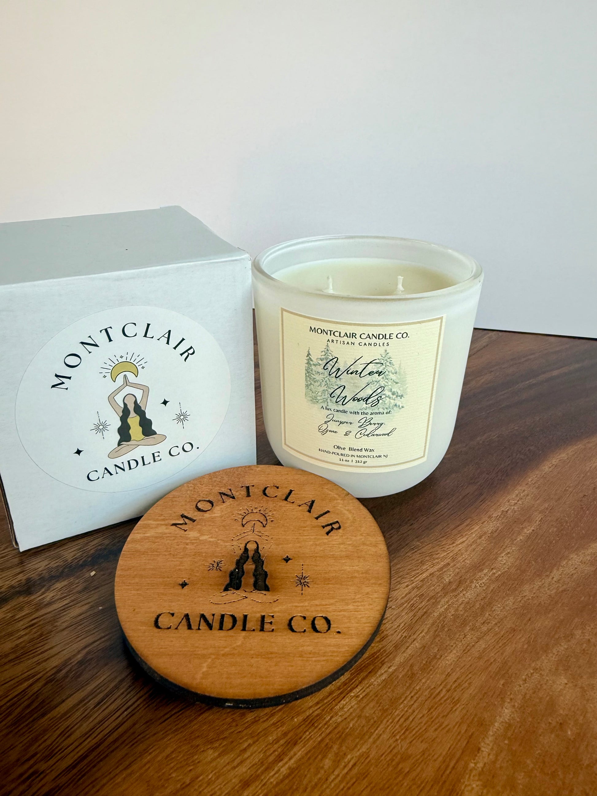 Montclair Candle Co. candle with wooden lid and branded box on a wooden surface