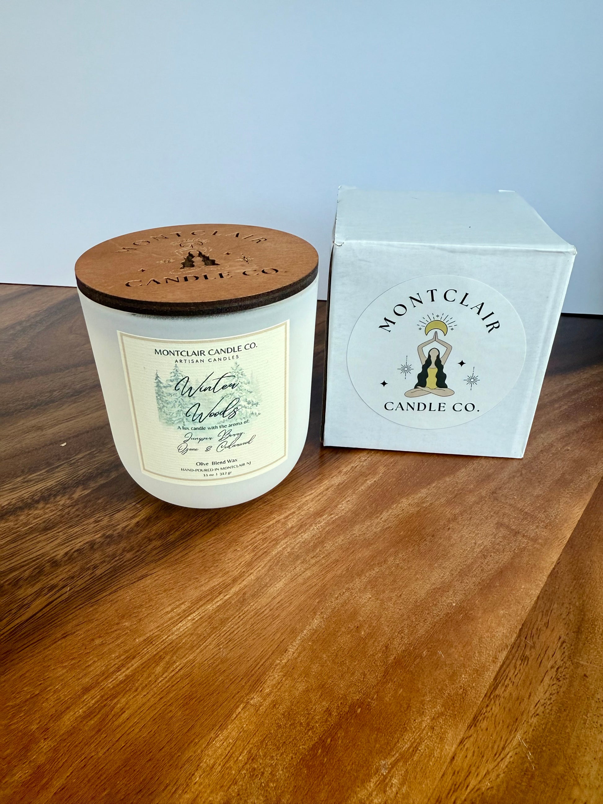 Montclair Candle Co. candle with wooden lid and packaging on a wooden surface